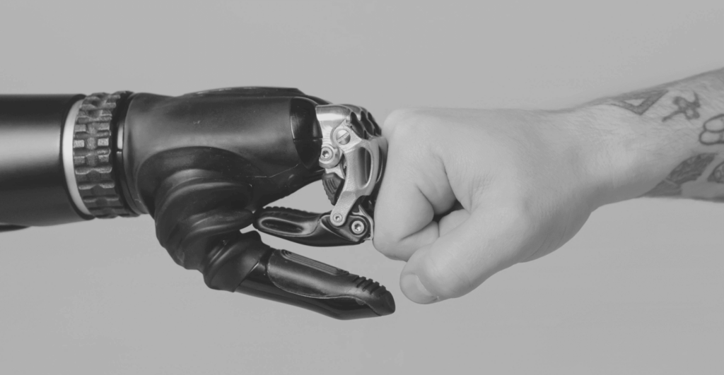 This image of a robotic hand connected with a human one illustrates our discussion topic: AI and risk management for modern businesses.