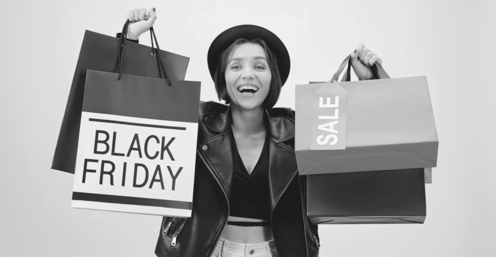 This image of a lady holding shopping bags adorned with Sales and Black Friday labels illustrates our discussion topic: scam surges during the Black Friday Sales, and how brands can protect themselves, their consumers, and their revenues.