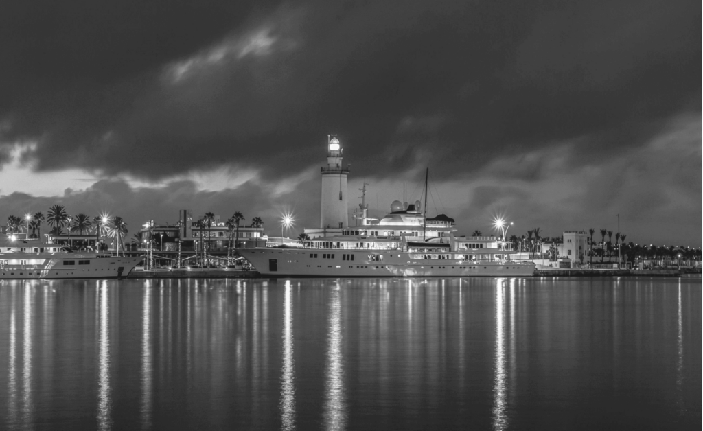 This image of an illuminated lighthouse on a dock next to a bustling port illustrates the future of brand threats in this brand protection guide.