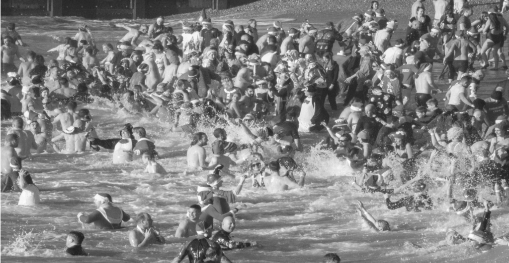 This image of a crowd in festive gear swimming in the sea illustrates our discussion topic: festive celebrations, and brand protection strategies, around the world.
