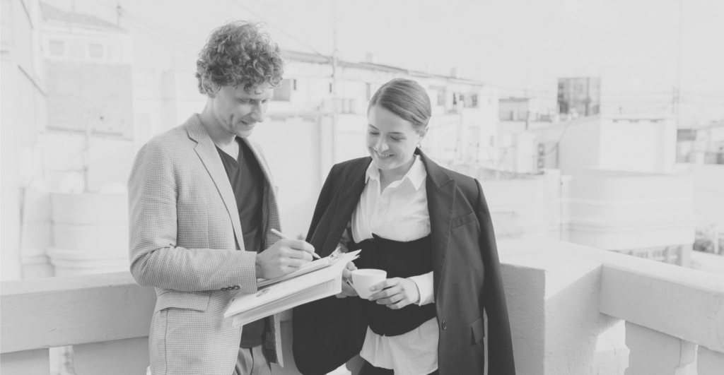 This image of two corporate analysts smiling and signing some documents illustrates this discussion topic: A counterfeits definition, and what it means for brands in the fight agains counterfeiting.