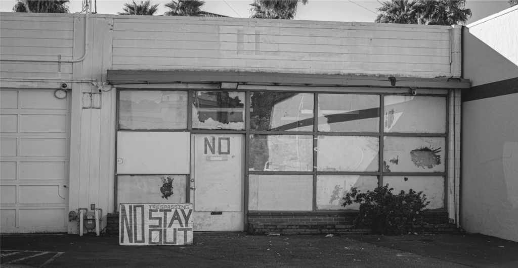 This image of a derelict house covered in graffiti and a sign saying "no trespassing, keep out" illustrates our discussion topic: Domain squatting, its impact, and anti-squatting solutions for organizations and individuals.