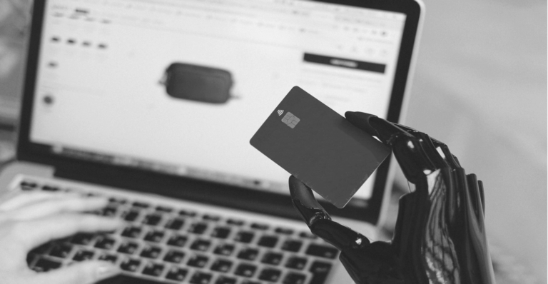 This image of a robot using a credit card on a computer illustrates our discussion topic: AI infringements, specifically around ecommerce fraud, and how businesses can fight back with insights from Lisa Deegan on our recent podcast.