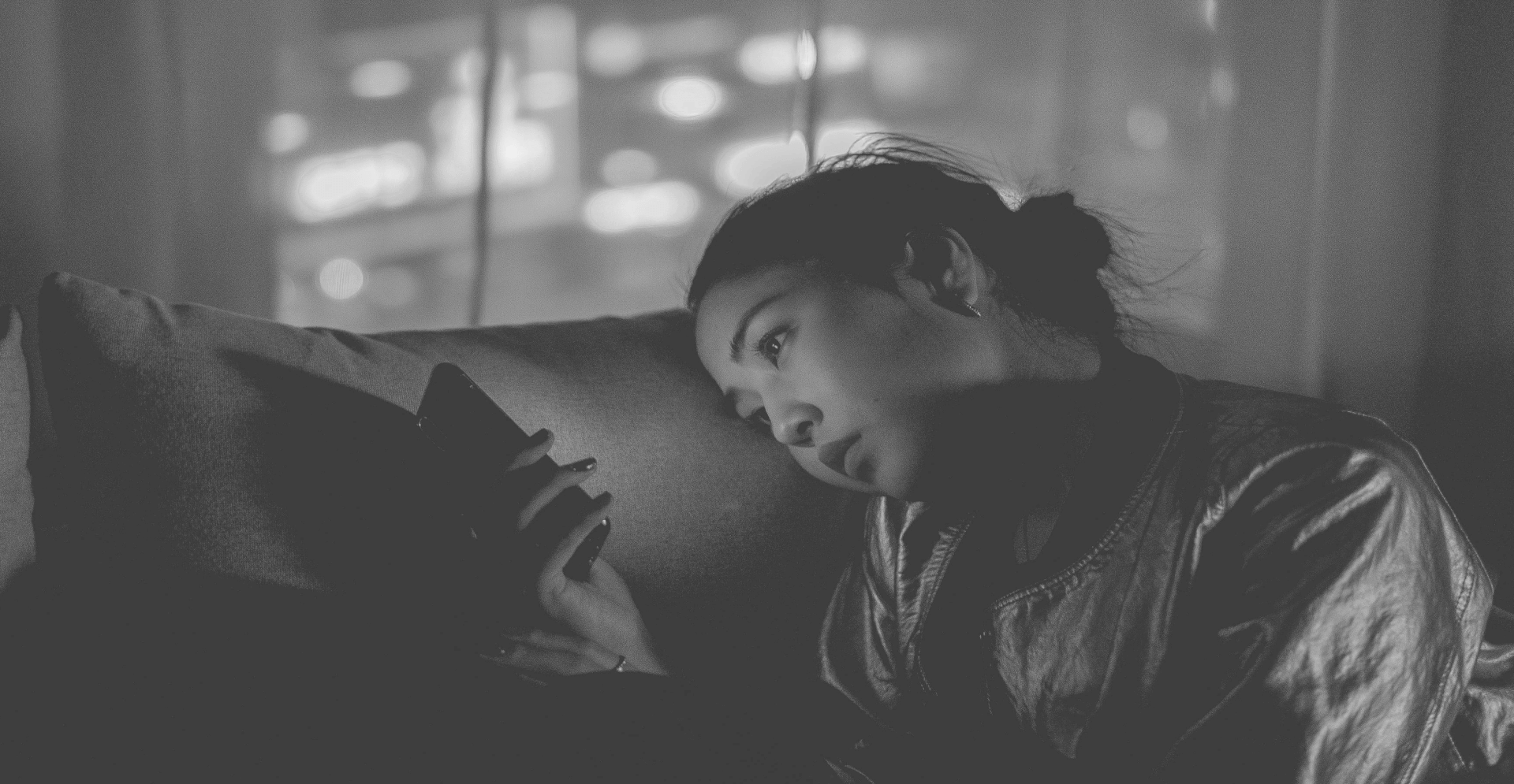 This image of a lady on a couch, browsing her phone, illustrates our discussion topic: social media monitoring, social media scams, and malicious ads that target brands.